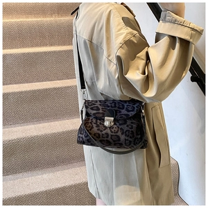 Detail of leopard print crossbody bag with silver buckle on brown trench coat