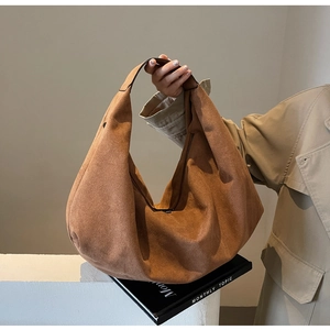 Brown suede hobo bag with large capacity and minimalist design shown in a casual lifestyle setting