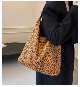 Grand sac cabas tendance à imprimé léopard porté avec un manteau noir minimaliste