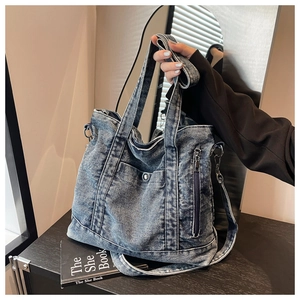 Close-up of vintage blue washed denim tote bag showing magnetic pocket and side zipper details