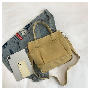 Detailed flat lay of a khaki canvas tote bag with front pocket and adjustable shoulder strap