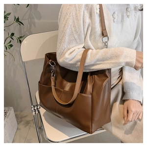 Detail of soft dark brown PU leather tote bag with silver ring hardware on a model