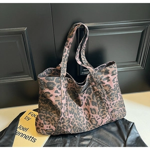 Detail of a large leopard print tote bag placed on a leather jacket in a stylish setting