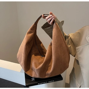 Detail of caramel brown suede crescent shoulder bag showing soft texture and metal zipper