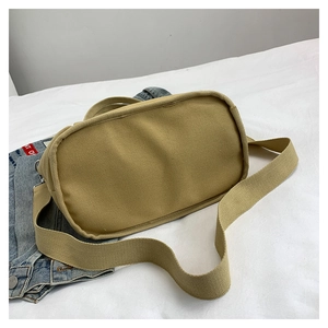 Detailed bottom view of a khaki thick canvas tote bag with a wide woven shoulder strap
