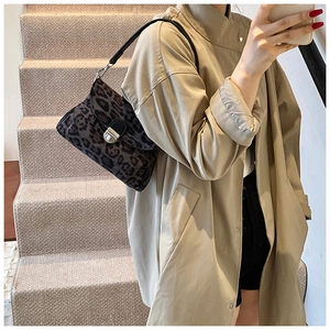 Detail of leopard print shoulder bag with silver clasp and black leather strap on model