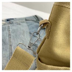 Close-up of durable khaki canvas bag showing silver metal lobster clasp and reinforced stitching