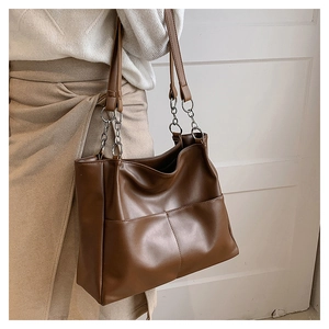 Detail view of brown PU leather tote bag with silver chain strap and front pockets
