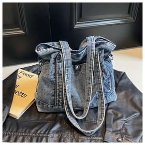 Detailed texture of retro washed blue denim tote bag resting on a black leather jacket