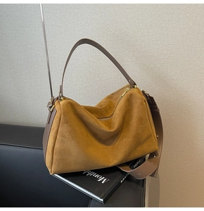 Close-up of the vintage brown suede texture and smooth leather handle on this baguette bag
