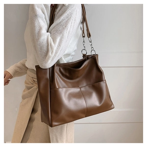 Detail of brown PU leather tote bag featuring mixed chain strap and front pocket
