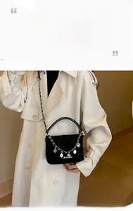 Detail of black quilted leather crossbody bag with decorative charms and gold handle