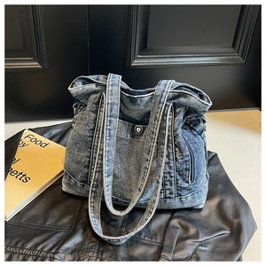 Detail of stone washed denim tote bag featuring dual handles and metal rivet pocket