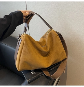 Close-up of ginger suede texture and brown leather strap on a large baguette bag
