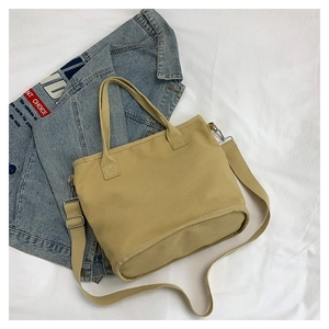 Detail view of khaki canvas tote with adjustable strap and textured fabric on white background