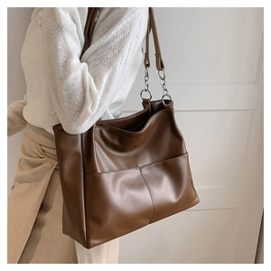 Close-up of a large brown tote bag with premium leather texture and silver chain strap
