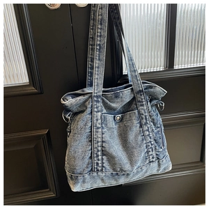 Detail of vintage washed denim tote bag showing metal button pocket and fabric texture