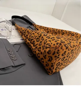 Détail d'un sac cabas léopard avec bandoulière en cuir noir sur un blazer gris
