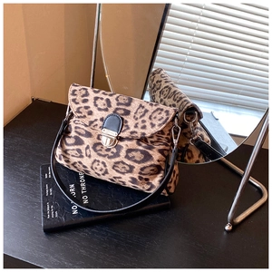 Detail of leopard print handbag with metallic clasp and leather strap against mirror