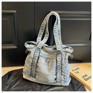 Detailed close-up of light blue vintage washed denim tote bag with functional pockets