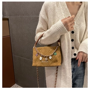 Close-up of caramel suede quilted handbag with decorative gold chain and heart charms