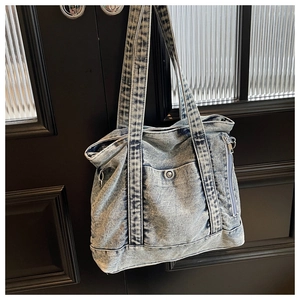 Detail of light blue washed denim tote bag hanging on black wooden door with magnetic pocket