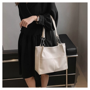 Chic cream tote bag with metal chain strap shown on model against minimalist background