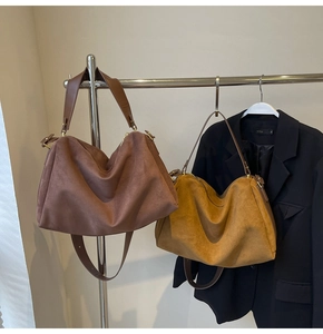 Detailed view of coffee and yellow faux suede hobo bags featuring wide shoulder straps
