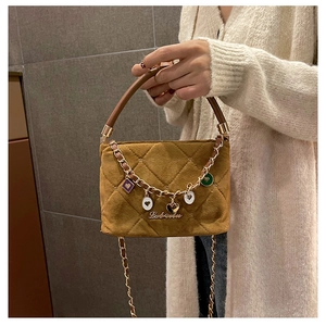 Detail of a brown quilted suede handbag featuring gold charms and chain shoulder strap