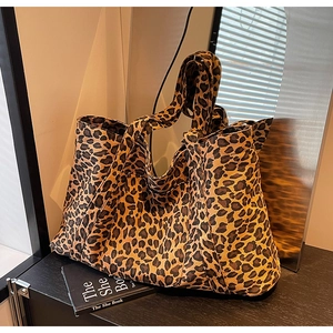 Detail of a large leopard print tote bag placed on a shelf with warm ambient lighting