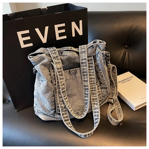 Close-up of vintage washed denim tote bag with side zippers and adjustable strap