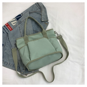 Detail of mint green canvas tote with multi-pockets and adjustable shoulder strap
