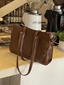 Minimalistische braune Tragetasche mit Schleifendetail in gemütlicher Café-Atmosphäre