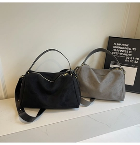 Detail of suede baguette bags in black and grey with adjustable straps and gold zippers