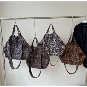 Close-up of four leopard print tote bags in various tones hanging on a metal rack