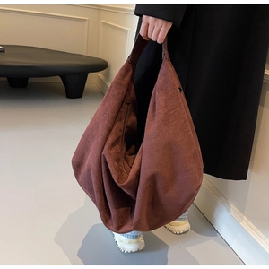 Detail of a large reddish-brown suede tote bag featuring a minimalist draped design and soft texture