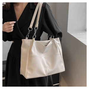 Close-up of cream white tote bag with metal chain shoulder strap and front pockets