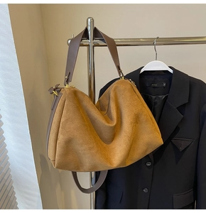 Macro detail of camel suede tote bag showing zipper closure and brown faux leather handle