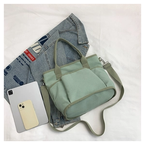 Top view of green canvas tote bag with large front pockets, adjustable strap and gadgets