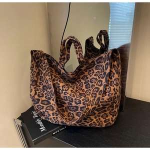 Detailed close-up of large leopard print tote bag with thick canvas texture and shoulder strap