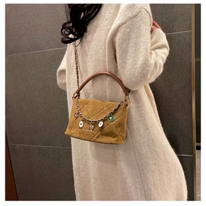 Detail of ginger yellow quilted handbag with leather chain strap and metal heart charms