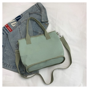 Detail view of light green canvas tote bag with detachable strap on denim background