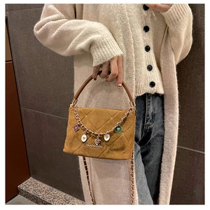 Close-up of mustard yellow quilted suede bag with heart charm chain and Lebaida logo