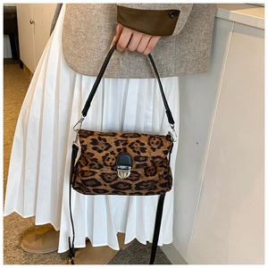 Detail view of leopard print crossbody bag with silver metal lock on model shoulder