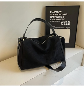 Close-up of black suede baguette bag with zipper closure and gold-tone metal hardware