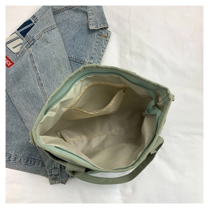 Detail view of the green canvas tote interior featuring zipper closure and inner pocket