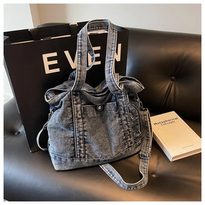 Detail of vintage washed blue denim tote bag featuring silver snap button pocket and wide strap