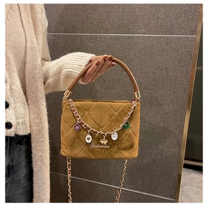 Macro detail of caramel quilted velvet handbag with metal chain and heart charm