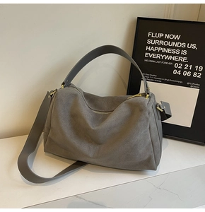 Macro detail of grey suede baguette bag with leather strap and metallic buckles