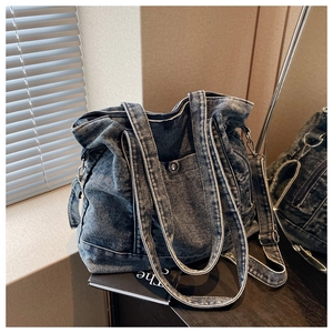 Detail of vintage washed blue denim tote bag with metal buckles and adjustable strap